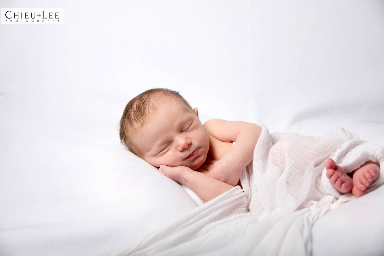 Half body newborn baby girl sleeping eyes closed white wrap on white blanket