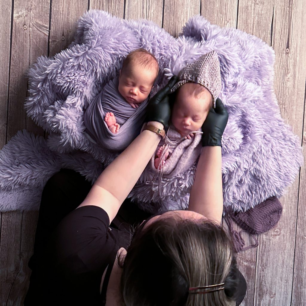 chieu lee putting a purple lavender bonnet on a newborn baby girl wrapped in purple